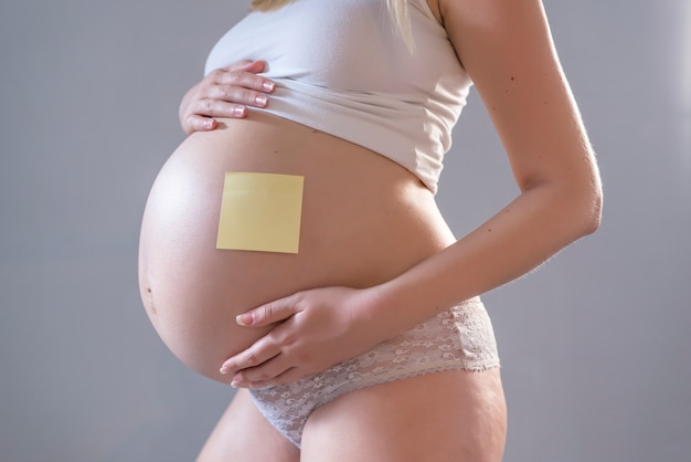 Pregnant woman with notepaper on her belly 