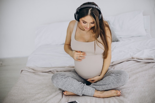 Pregnant woman with ultrasound photo listening to music