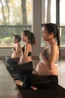 Free photo pregnant women practicing yoga together