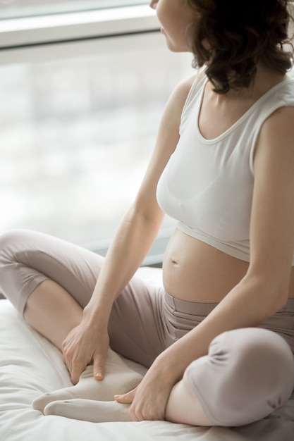 Foto gratuita donna incinta di yoga che fa posa di farfalla