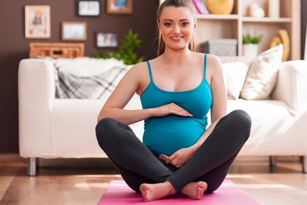 Pregnant young woman doing yoga at home