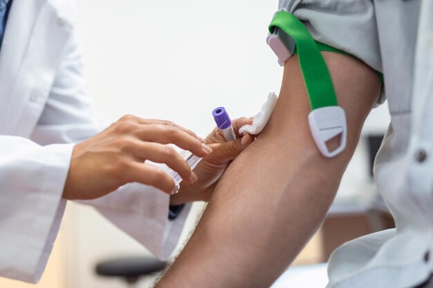 Preparation for blood test by female doctor medical uniform on the table in white bright room Nurse pierces the patient's arm vein with needle blank tube