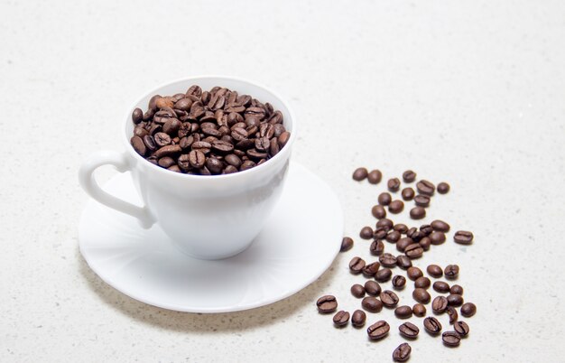 Preparation of coffee. coffee beans in a white cup. on light background