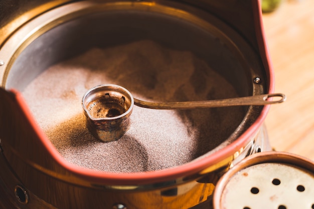 Preparation of turkish coffee in the cezve on sand at cafe bar