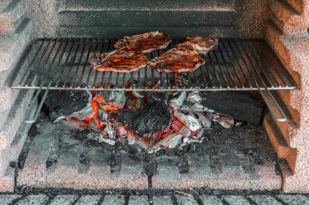 Prepared pork fillets being cooked over coals in barbecue