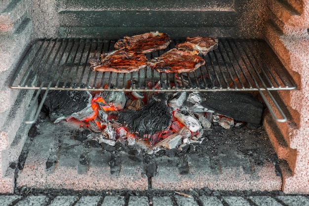 Prepared pork fillets being cooked over coals in barbecue