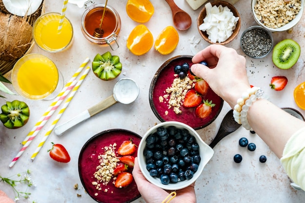 Preparing acai bowl in flat lay style with tropical fruits and grains