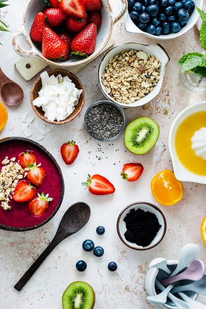 Preparing acai bowl in flat lay style with tropical fruits and grains