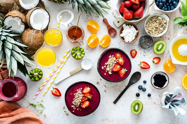 Preparing acai bowl in flat lay style with tropical fruits and grains