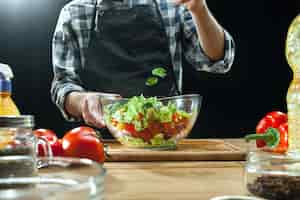 Foto gratuita preparare l'insalata. cuoco unico femminile che taglia le verdure fresche. processo di cottura. messa a fuoco selettiva