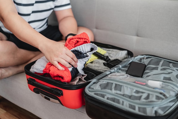 Preparing suitcase for summer vacation trip Young man checking accessories and stuff in luggage Travel holiday and vacation concept