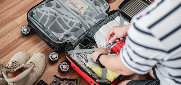 Preparing suitcase for summer vacation trip Young man checking accessories and stuff in luggage Travel holiday and vacation concept