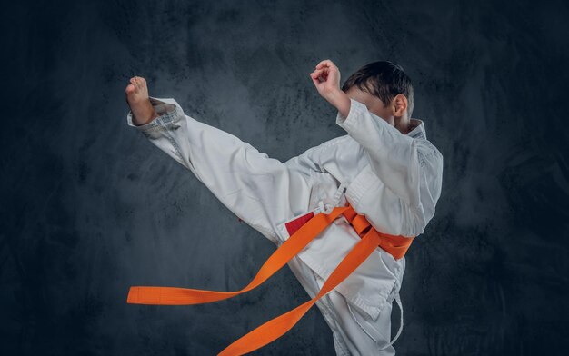 Preschooler boy dressed in a white karate kimono with orange belt.