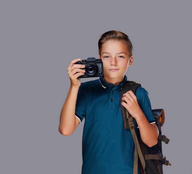 Preschooler boy taking pictures with a professional photo camera. Isolated on grey background.