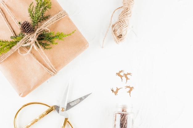 Present box in craft paper with coniferous twig near scissors 