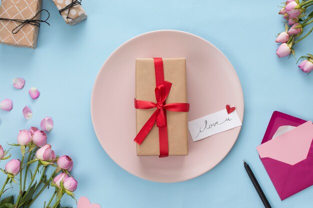 봉투와 꽃 사이의 접시에 선물 상자