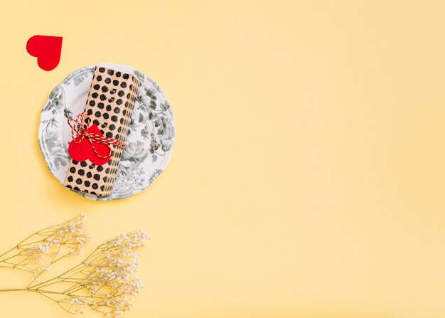 Present box on plate, ornament heart and plants