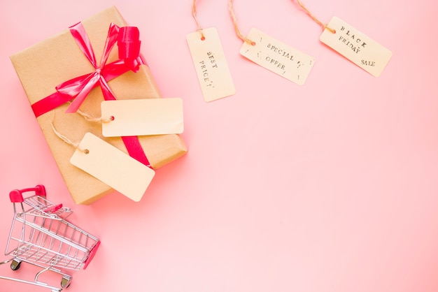 present box with bow near shopping trolley and sale labels