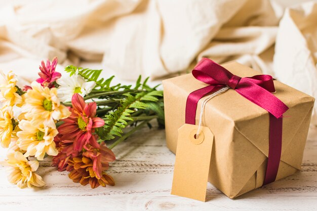茶色のタグとテーブルの上の花の束のプレゼントボックス