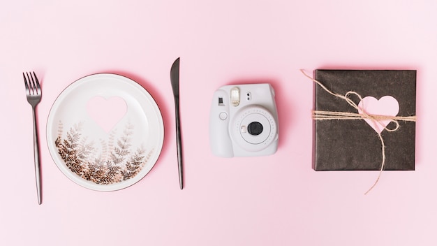 Free photo present box with ornament heart, camera, plate and cutlery