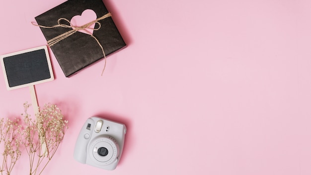 Present box with ornament heart, camera, twig and tablet 