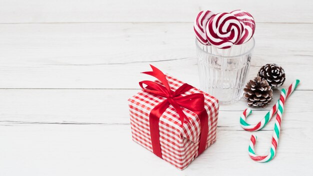 Present box in wrap near glass with lollipops and candy canes 