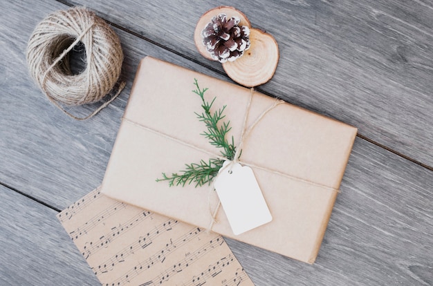 Present box in wrap near post card and bobbin of thread