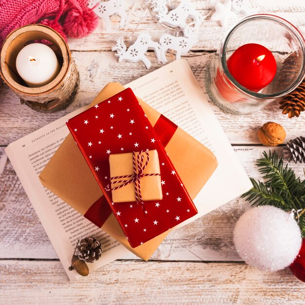 Present boxes on book near burning candles on wood board