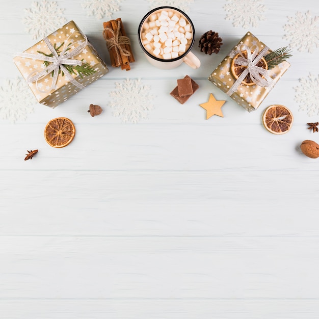 Present boxes in Christmas wrap near cup with marshmallows 