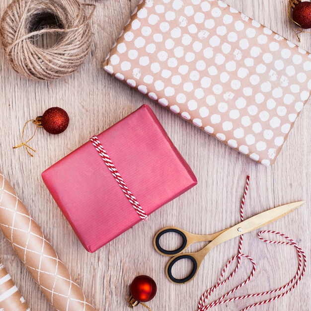 クリスマスボール、糸、はさみのそばを包むプレゼント
