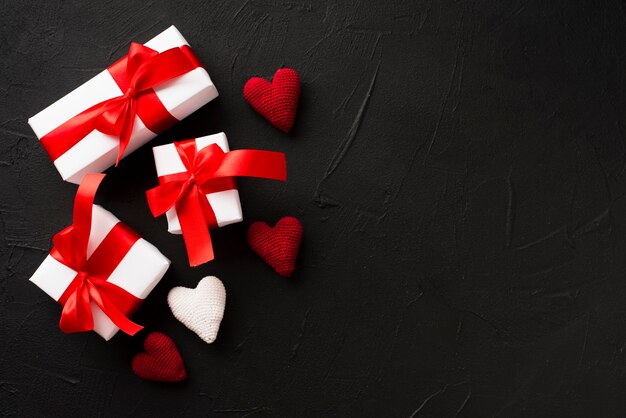 Presents and knitted hearts on black background