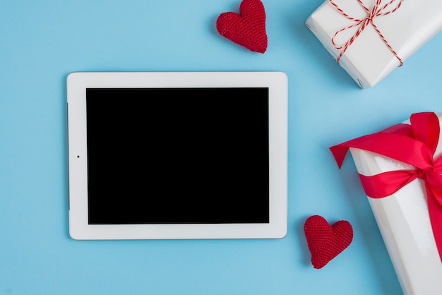 Presents and knitted hearts near modern tablet