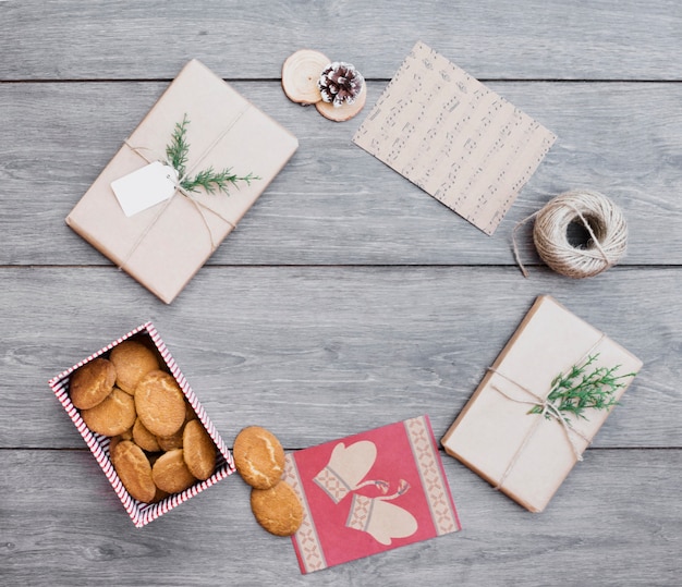 Presents near cookies in box, post cards and bobbin of thread