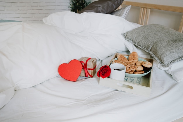 Regali e rose vicino a colazione sul letto