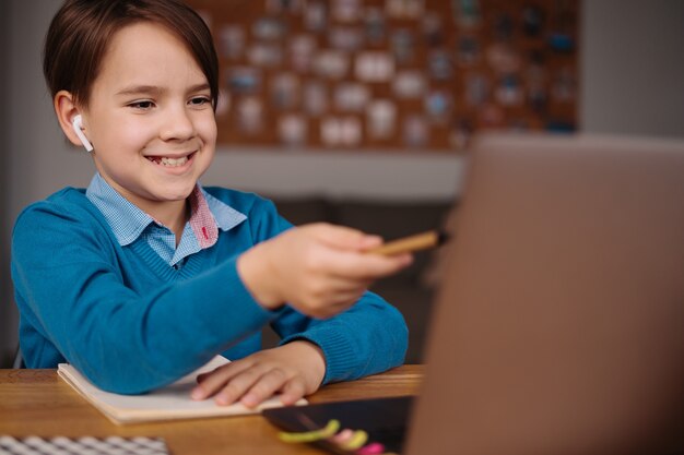 A Preteen boy uses a laptop to make online classes