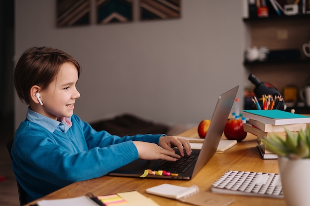 A Preteen boy uses a laptop to make online classes