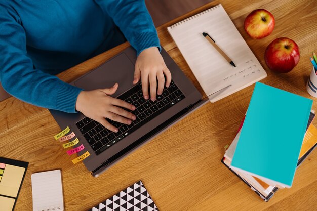 A Preteen boy uses a laptop to make online classes