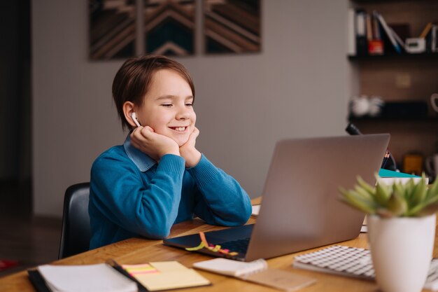 プレティーンの少年がラップトップを使用してオンラインクラスを作成する