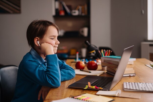 A Preteen boy uses a laptop to make online classes