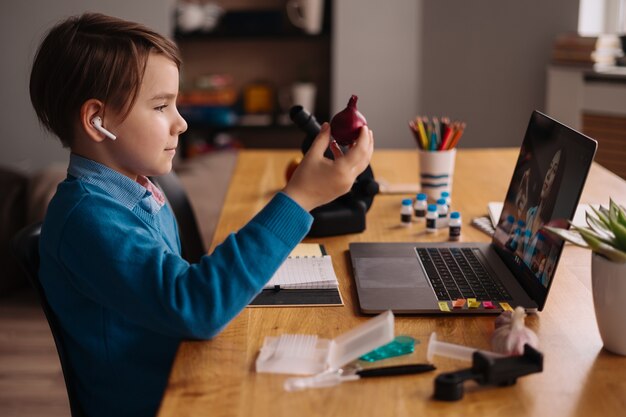 Free photo a preteen boy uses a laptop to make a video call with his teacher