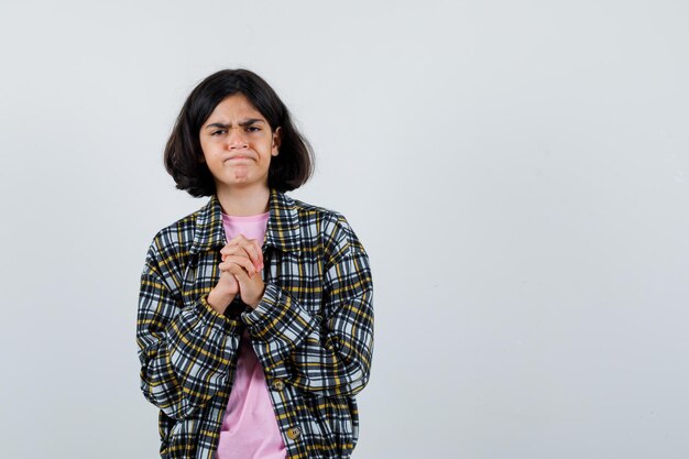 Preteen girl expecting news while standing with combined hands in shirt,jacket and looking impatient. front view. space for text