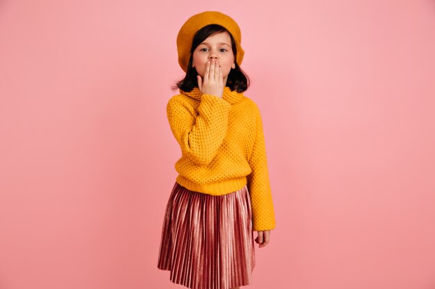 Preteen girl in knitted sweater sending air kiss.  funny kid in yellow clothes.