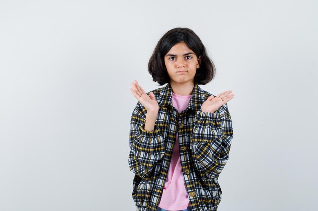 Preteen girl showing helpless gesture in shirt,jacket , front view.