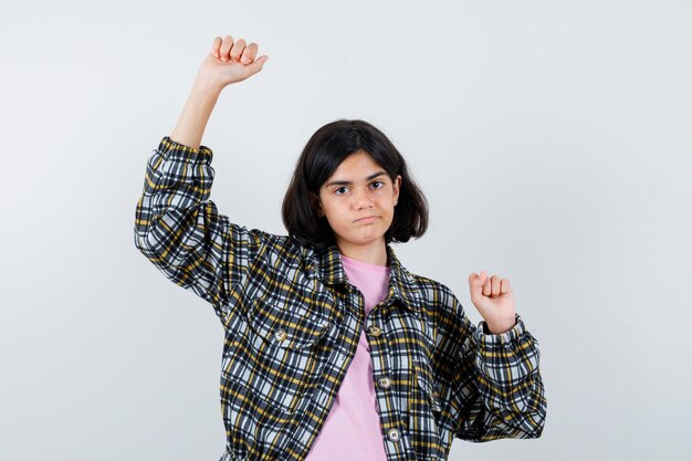 Preteen girl stretching arms in shirt,jacket and looking flexible. front view.