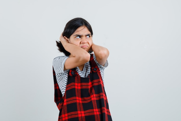 Preteen girl in t-shirt, jumpsuit clasping head with hands