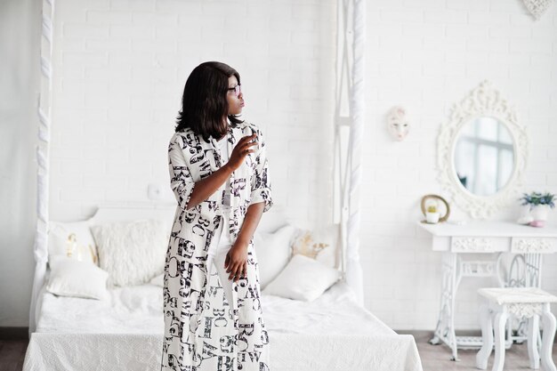 Довольно африканская американка в черно-белом платье в очках позирует в комнате