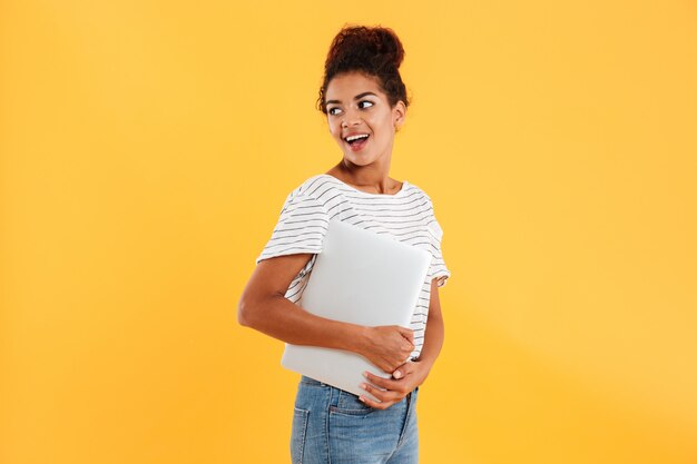 Pretty african lady holding laptop and looking aside