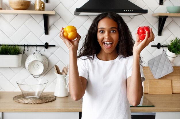 Pretty afro girl smiling holds two pepper