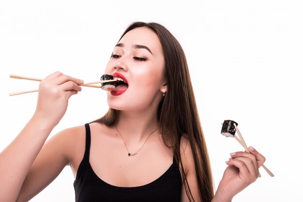 Pretty asian brunette eat sushi rolls with wooden chopsticks