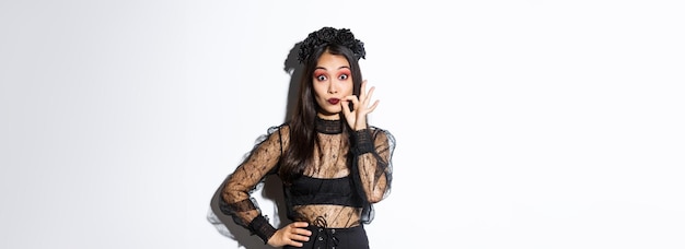 Foto gratuita bella ragazza asiatica in costume da strega che promette labbra di sigillo e mantiene la bocca segreta censurata